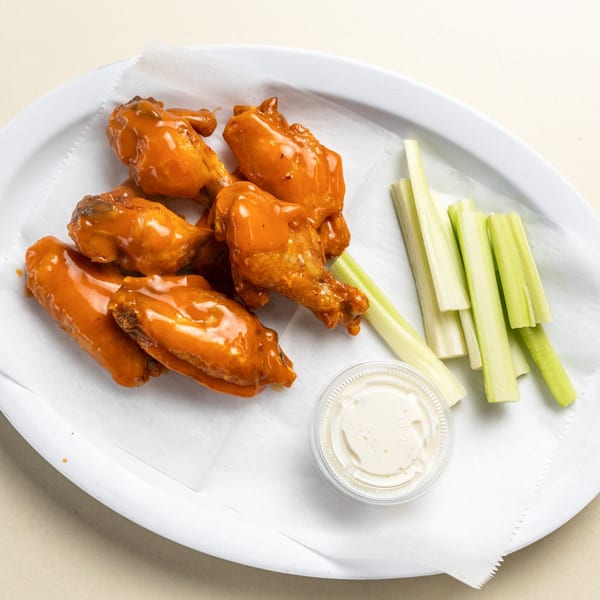 Randazzo's Pizzeria buffalo wings with celery sticks and a side of ranch dressing.